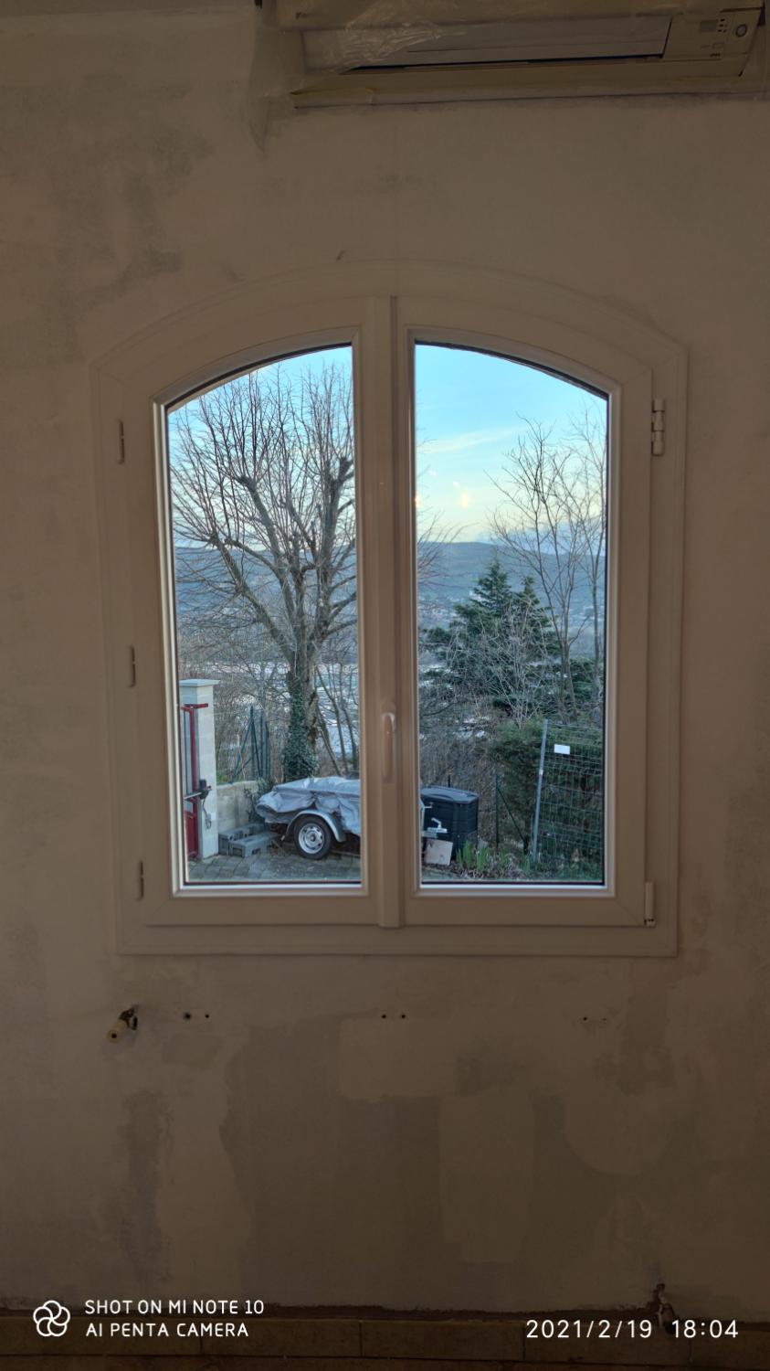 Fenêtre cintrée blanche, arbres et ciel au-delà