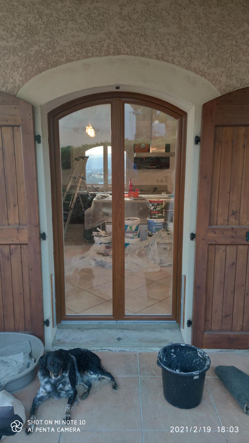 Porte-fenêtre cintrée aspect bois entre deux volets bois