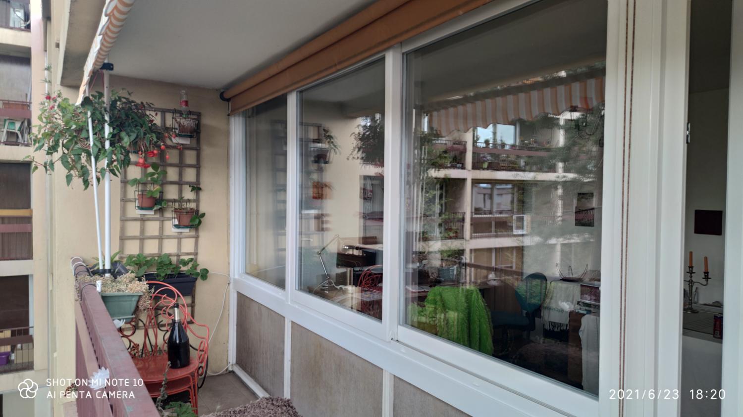 Façade vitrée blanche d’une loggia, balcon fleuri