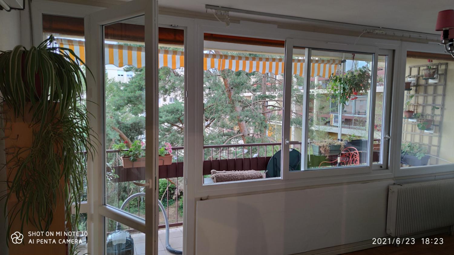 Séjour ouvert sur une loggia vitrée, stores rayés et plantes