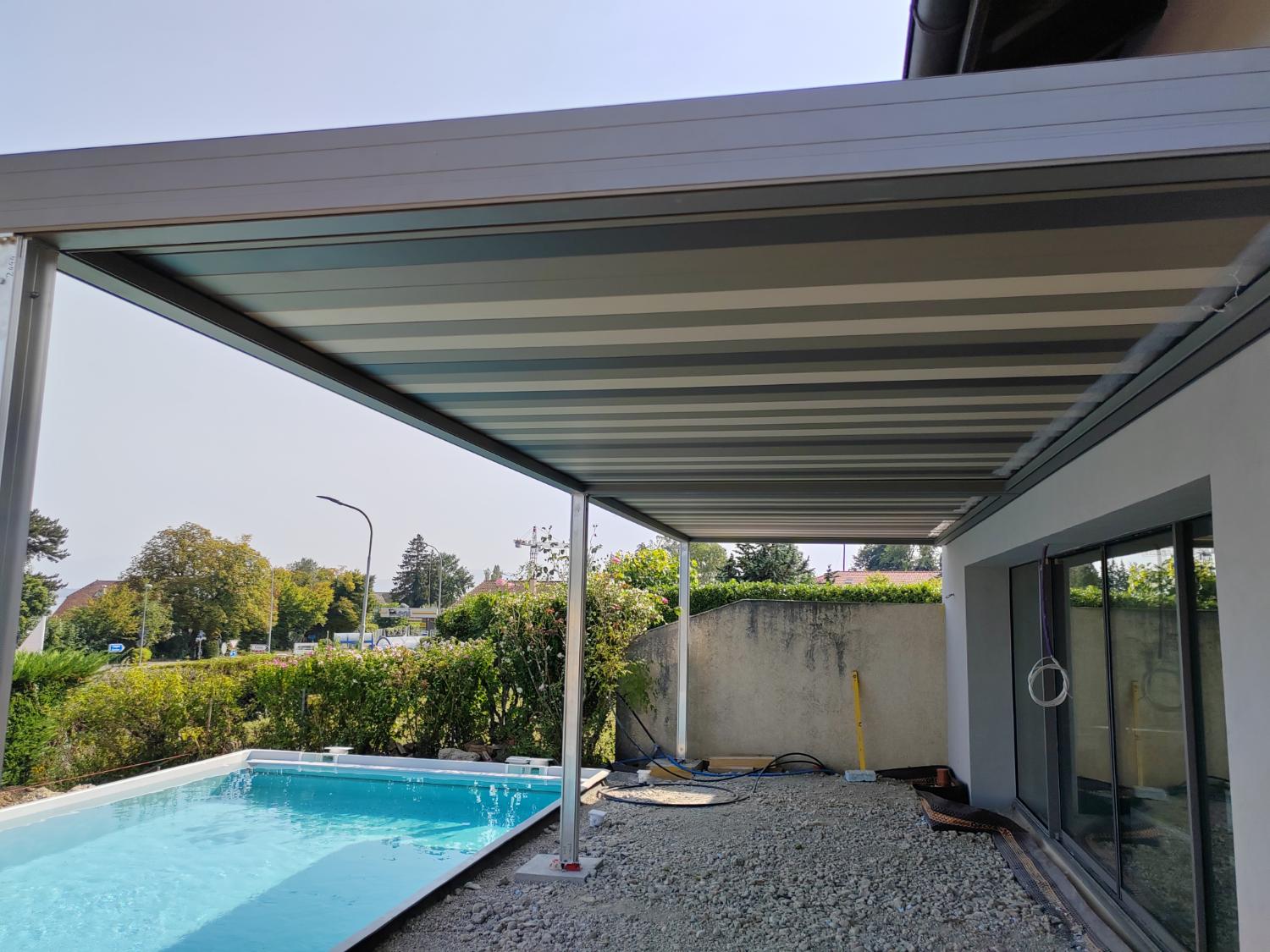 Pergola bioclimatique adossée à la maison, piscine au premier plan