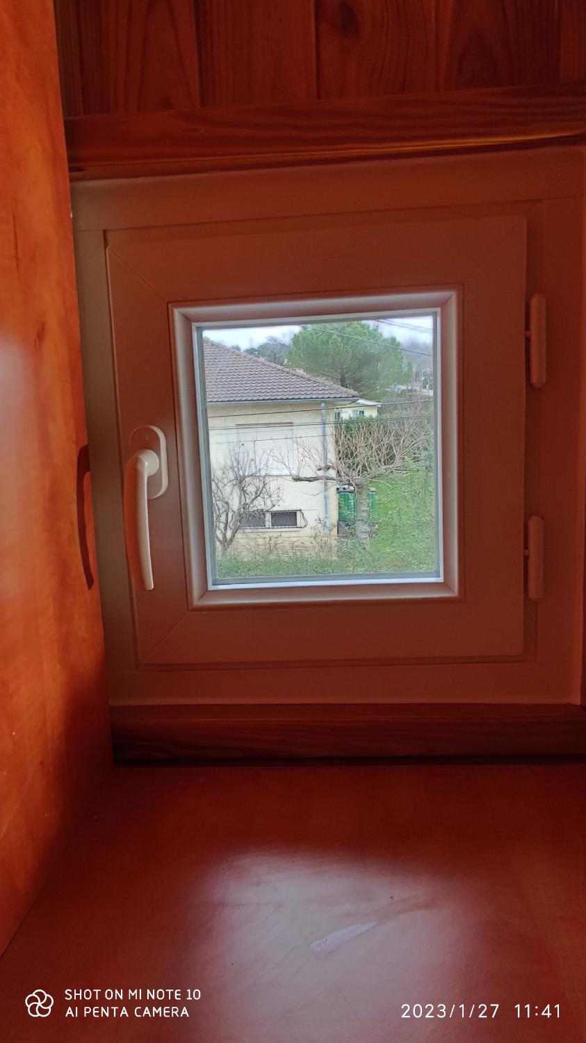 Petite fenêtre blanche posée dans un habillage bois